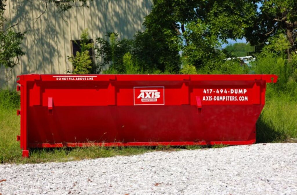 An Axis Dumpsters employee managing a roll-off dumpster rental in Rogersville, MO, demonstrating expert waste management solutions. Roll Off Dumpster Rental near me.